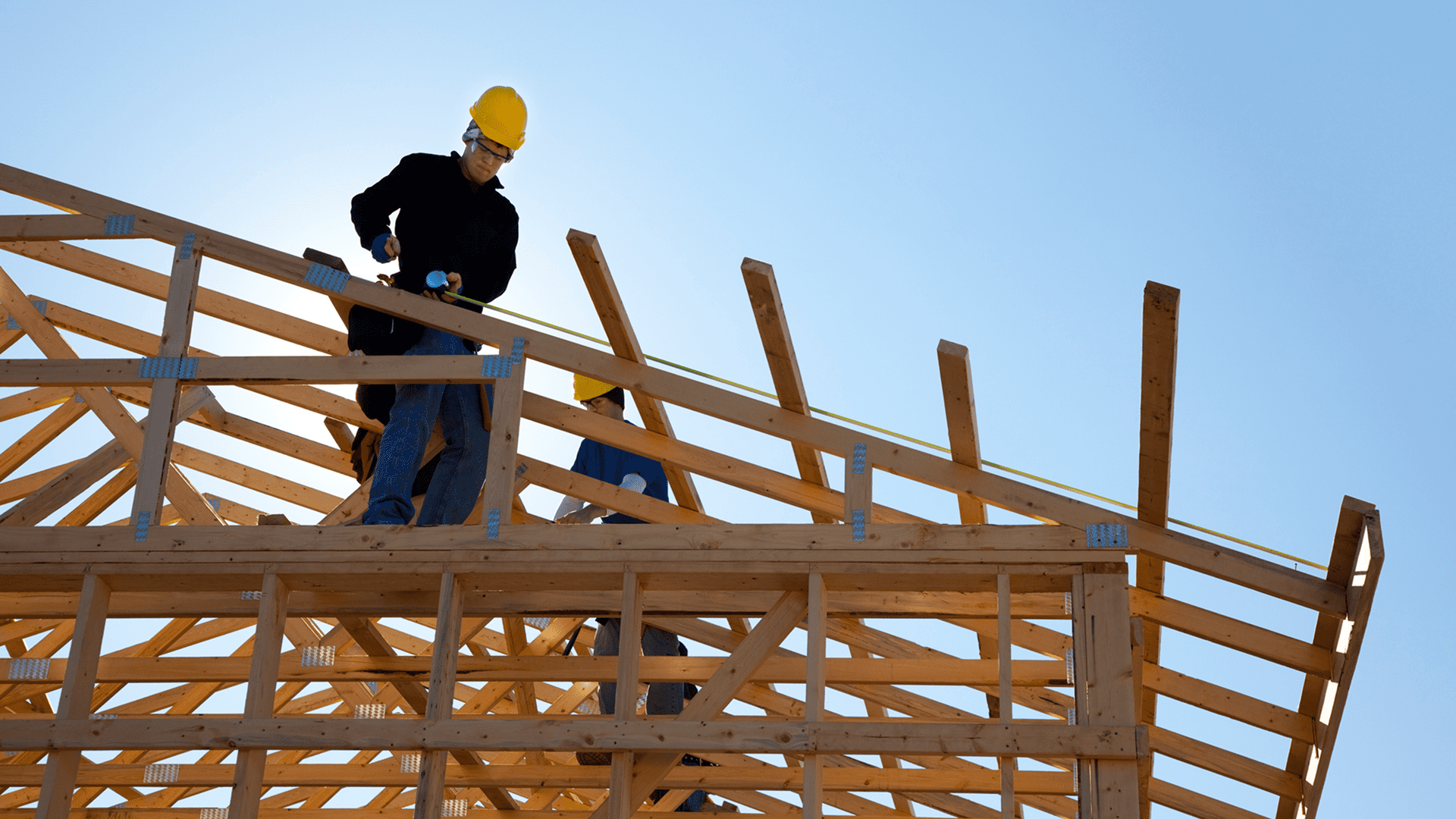 Construction workers assembling wooden roof trusses