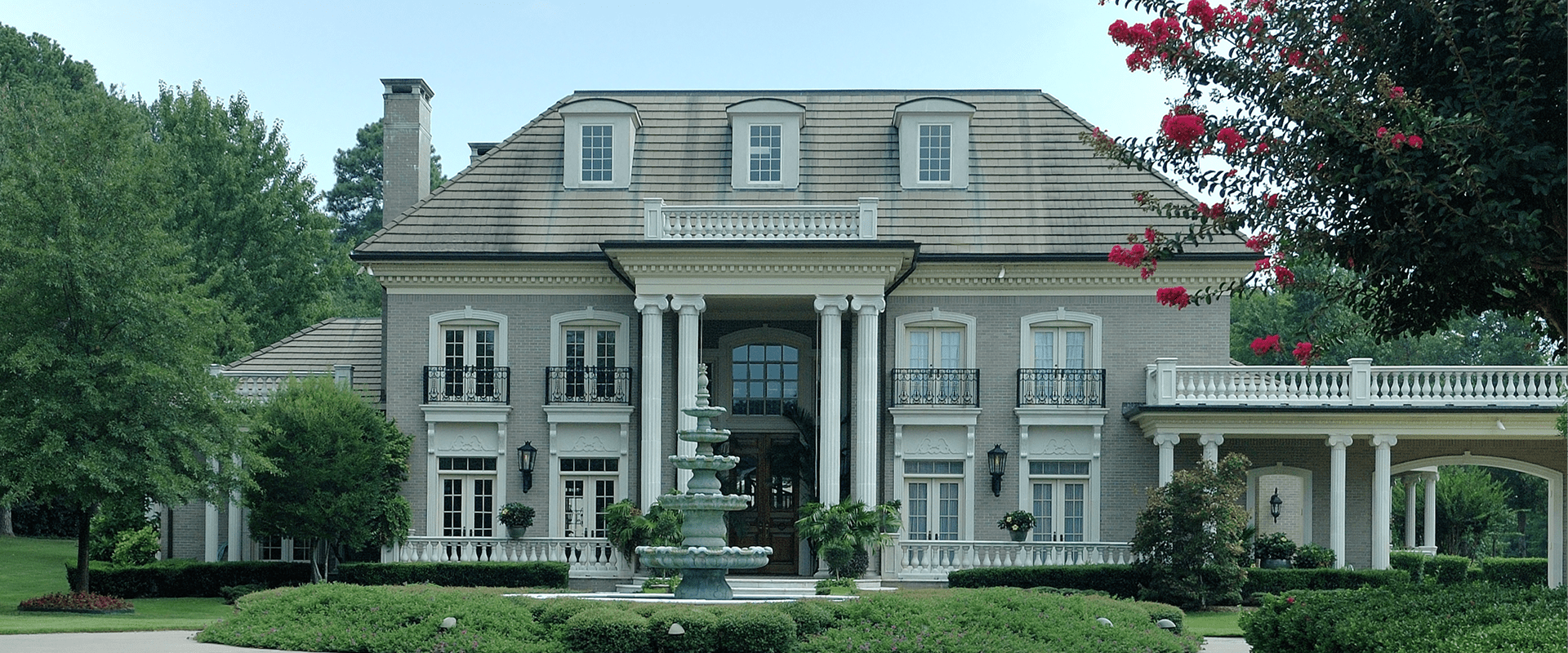 Grand gray mansion with fountain and columns