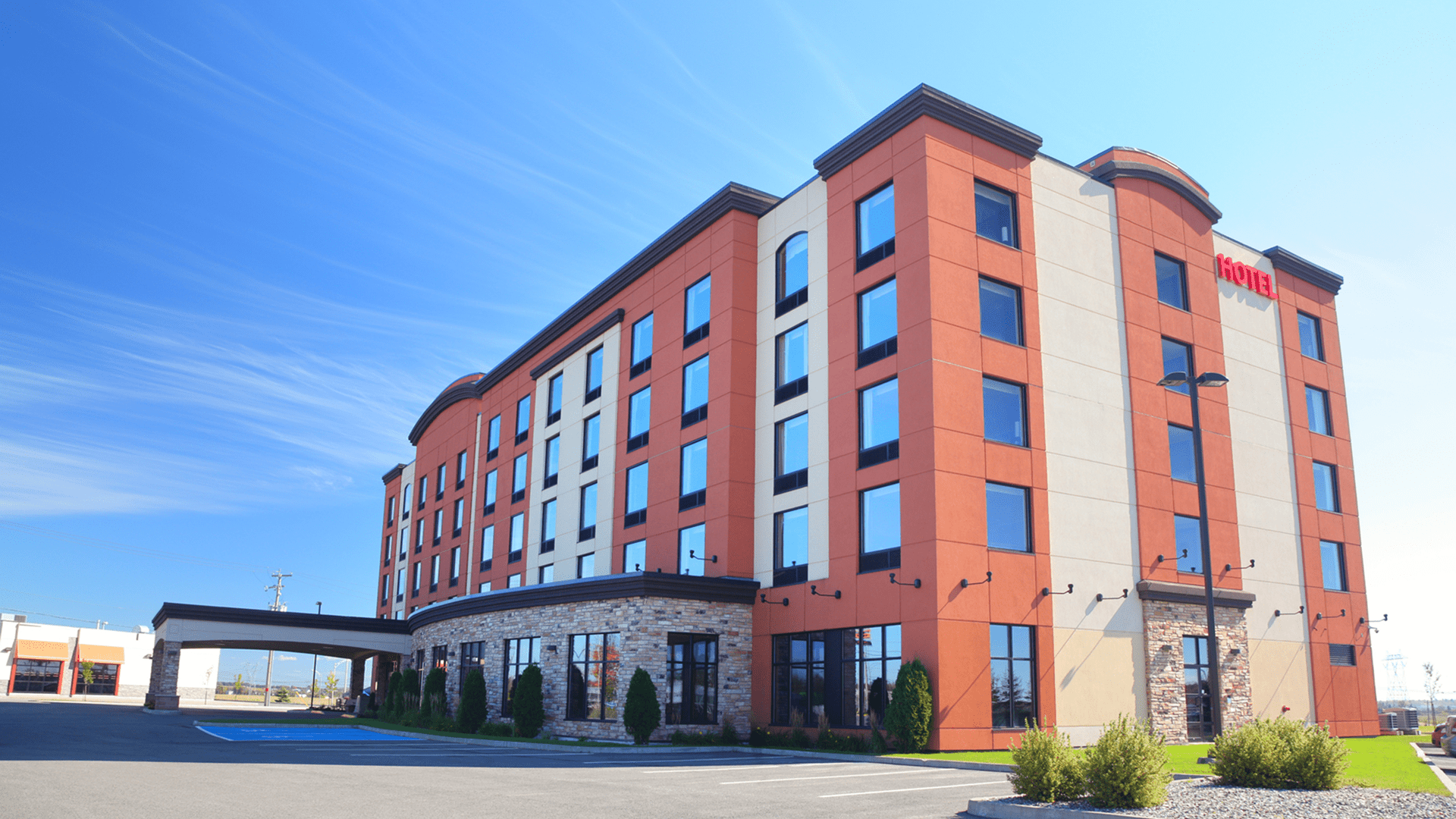 Modern red hotel building with entrance, blue sky