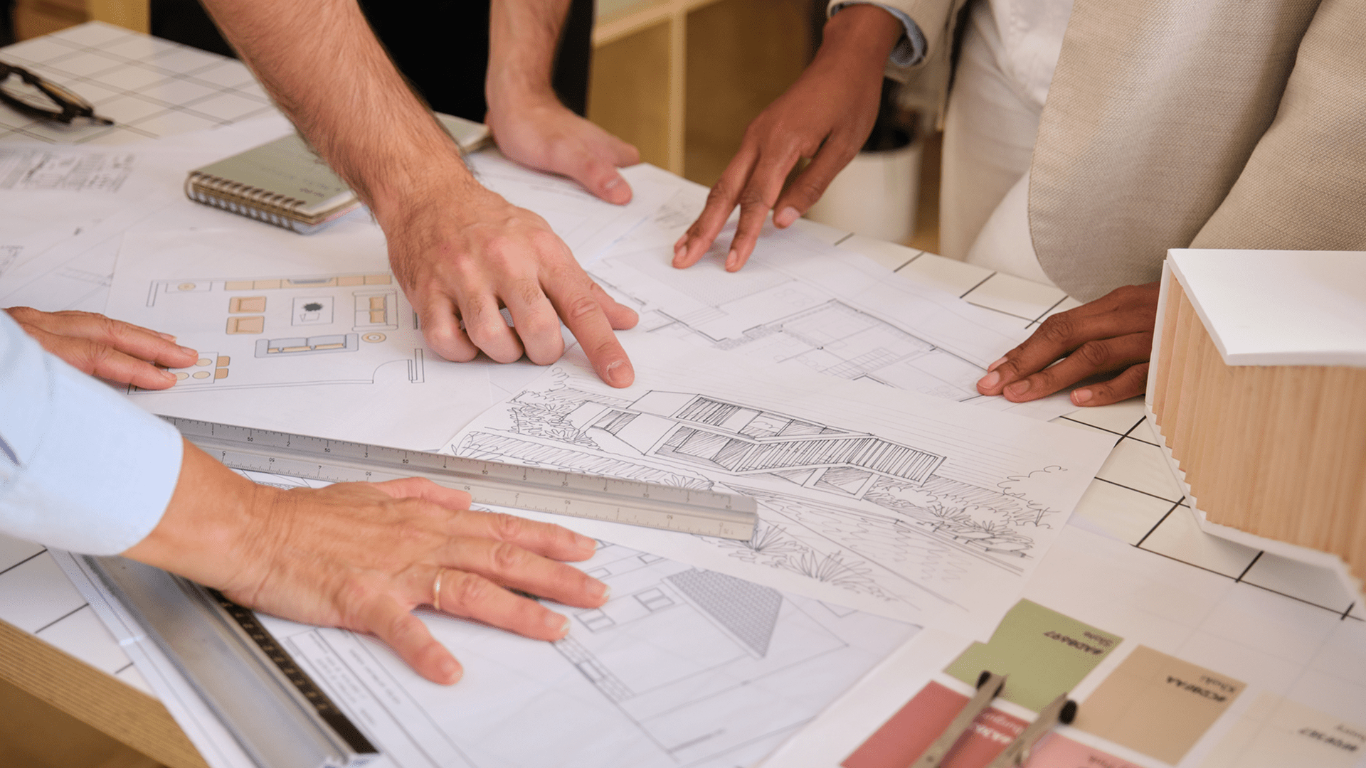 Hands pointing at architectural blueprints and model